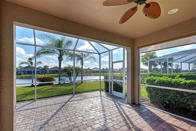 unfurnished sunroom with ceiling fan and a water view