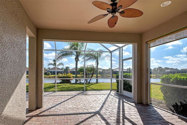 unfurnished sunroom with ceiling fan and a water view