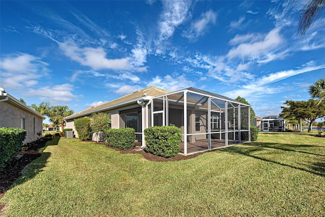 back of property with glass enclosure and a lawn