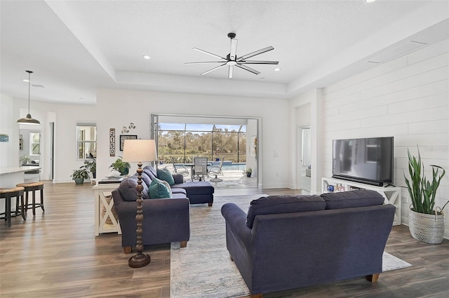 living room featuring dark wood-type flooring, a textured ceiling, an inviting chandelier, and a tray ceiling