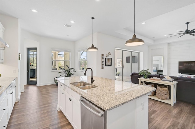 kitchen with sink, light stone countertops, white cabinets, decorative light fixtures, and stainless steel dishwasher