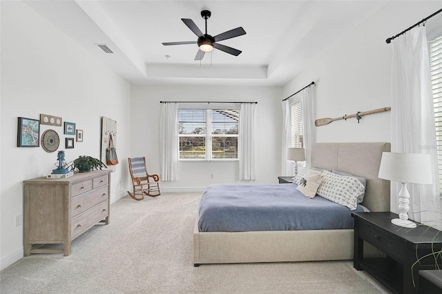 carpeted bedroom with a tray ceiling and ceiling fan