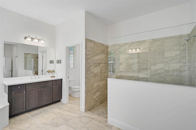 bathroom featuring vanity, a tile shower, and toilet