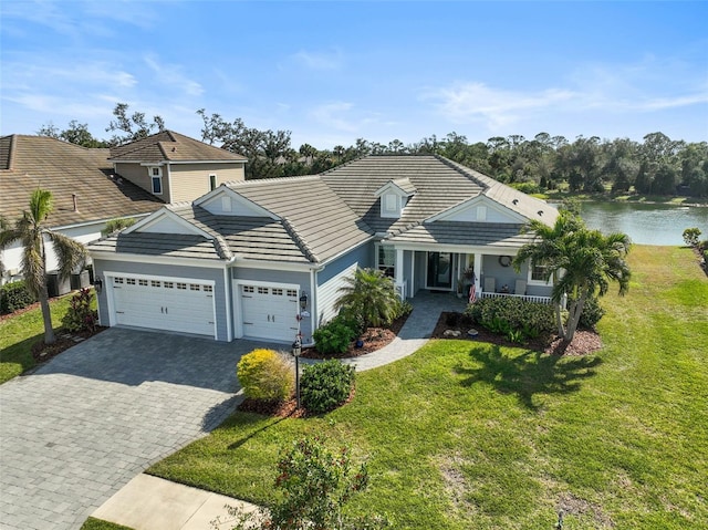 view of front facade with a garage, a water view, covered porch, and a front lawn