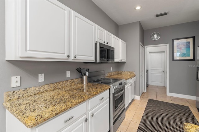 kitchen featuring white cabinetry, stainless steel appliances, light tile patterned flooring, and dark stone counters