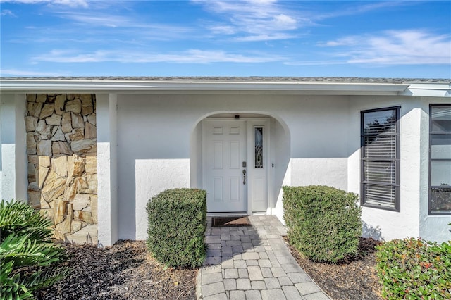 entrance to property featuring stone siding and stucco siding