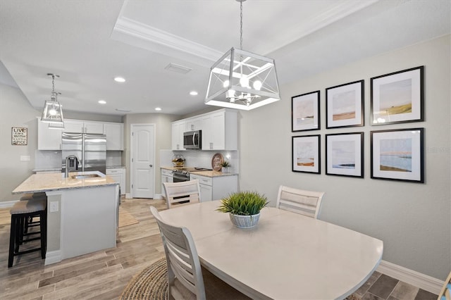 dining area featuring sink, a chandelier, and light wood-type flooring