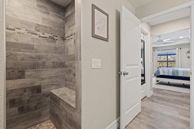 bathroom with a tile shower, wood-type flooring, and ceiling fan