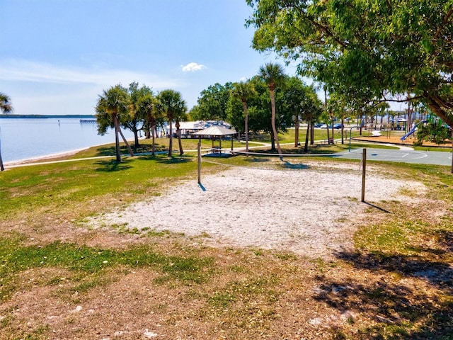 surrounding community featuring a playground, a lawn, basketball court, a gazebo, and a water view