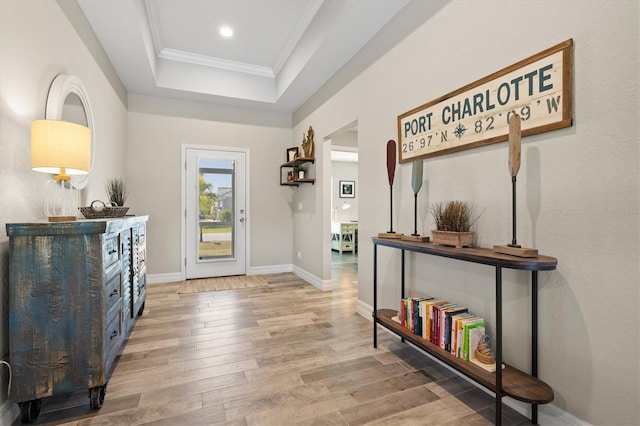 foyer entrance featuring a raised ceiling, wood-type flooring, and ornamental molding