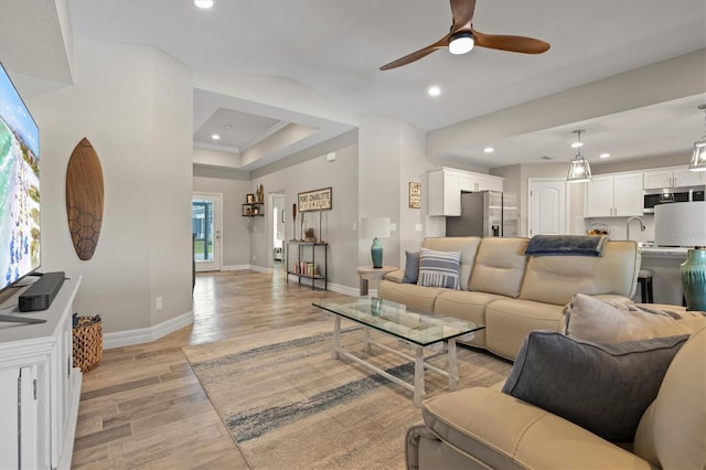 living room featuring ceiling fan, sink, and light hardwood / wood-style floors