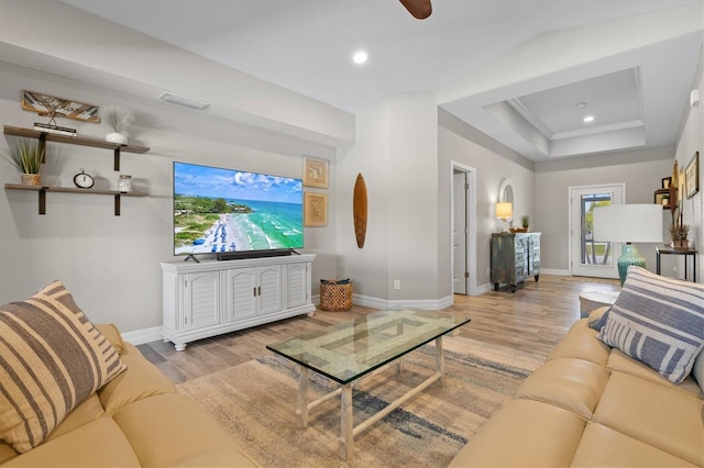 living room featuring crown molding, light hardwood / wood-style floors, and a raised ceiling