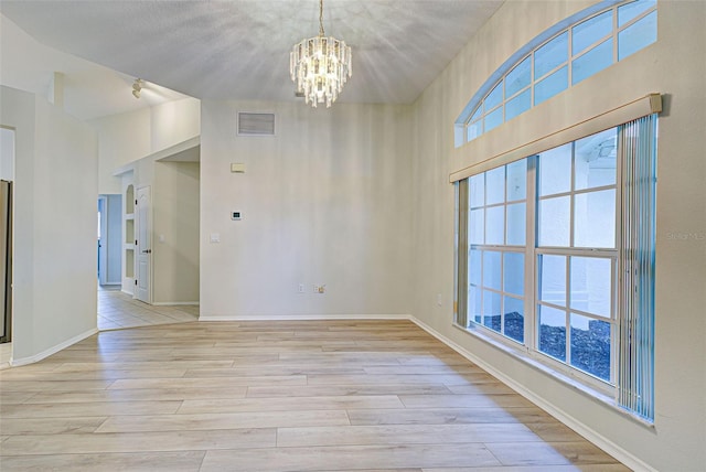 unfurnished room with a chandelier and light wood-type flooring