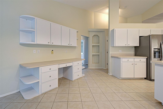 kitchen with white cabinetry, light tile patterned flooring, stainless steel refrigerator with ice dispenser, and a high ceiling