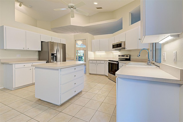 kitchen featuring lofted ceiling, sink, stainless steel appliances, a center island, and white cabinets