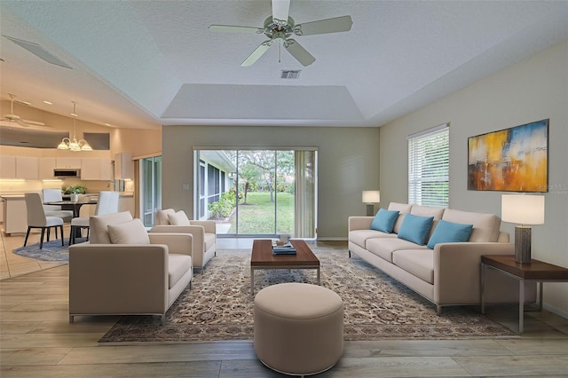 living room featuring ceiling fan, a textured ceiling, and a tray ceiling