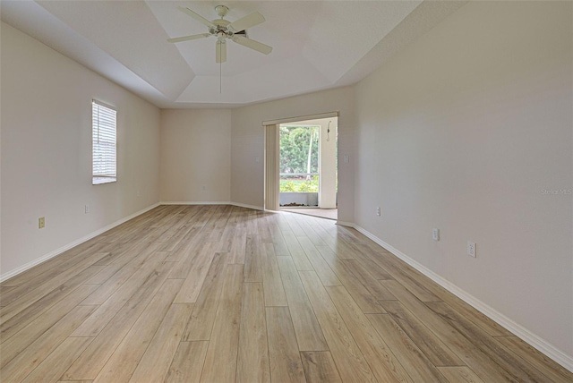 empty room featuring light hardwood / wood-style flooring, a raised ceiling, and ceiling fan