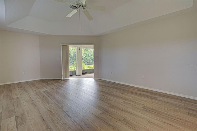 empty room with light hardwood / wood-style flooring, ceiling fan, and a tray ceiling