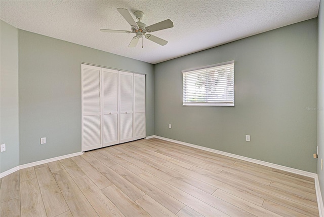 unfurnished bedroom with light wood-type flooring, a textured ceiling, ceiling fan, and a closet