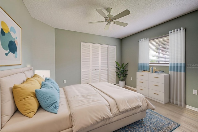 bedroom featuring ceiling fan, a closet, a textured ceiling, and light wood-type flooring