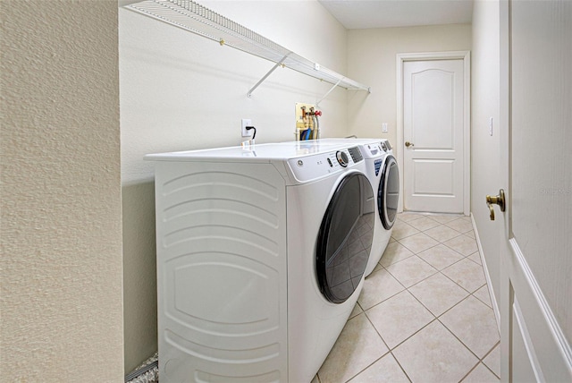 clothes washing area featuring separate washer and dryer and light tile patterned floors