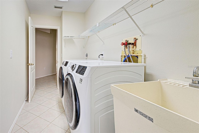 clothes washing area featuring sink, washer and dryer, and light tile patterned floors