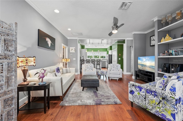 living room with ornamental molding, hardwood / wood-style floors, a textured ceiling, and ceiling fan