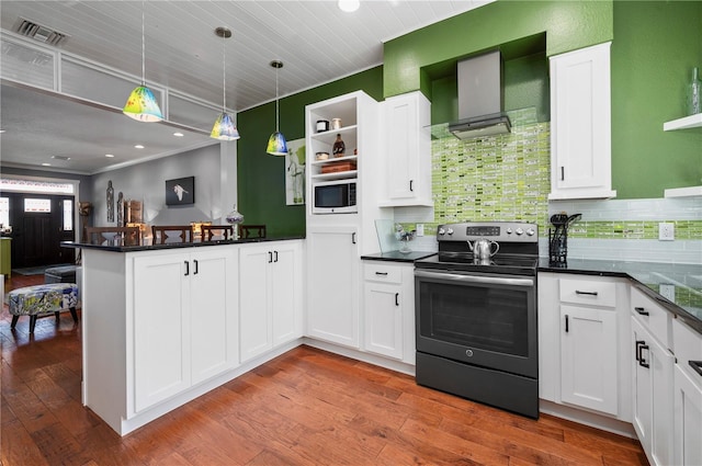 kitchen featuring decorative light fixtures, stainless steel electric range, kitchen peninsula, wall chimney range hood, and white cabinets