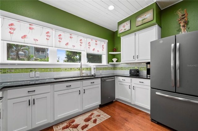 kitchen with appliances with stainless steel finishes, tasteful backsplash, white cabinetry, sink, and light hardwood / wood-style floors