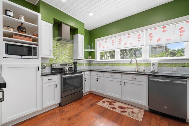 kitchen featuring white cabinetry, wall chimney range hood, stainless steel appliances, and sink