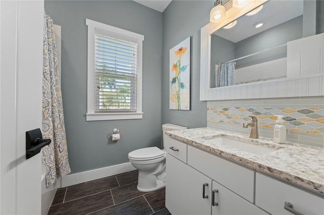 bathroom featuring walk in shower, vanity, toilet, and backsplash