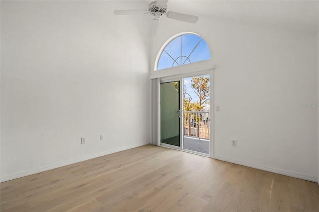 unfurnished room featuring a towering ceiling, ceiling fan, and light wood-type flooring