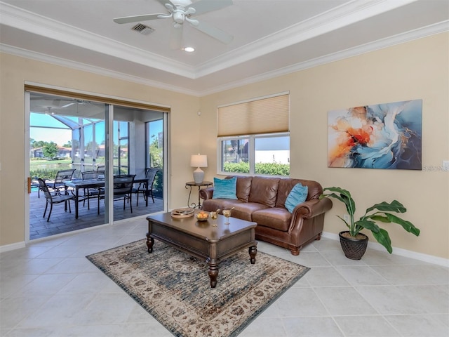 living room with crown molding, light tile patterned flooring, ceiling fan, and a tray ceiling