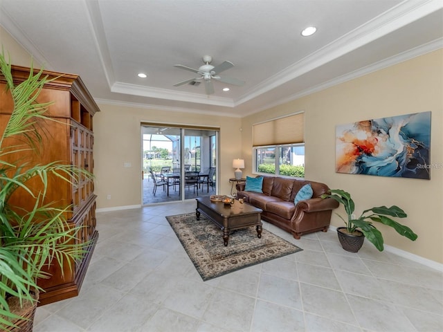 tiled living room featuring a tray ceiling, ornamental molding, and ceiling fan