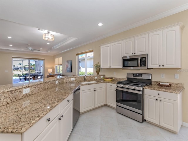 kitchen with sink, ornamental molding, appliances with stainless steel finishes, light stone countertops, and white cabinets