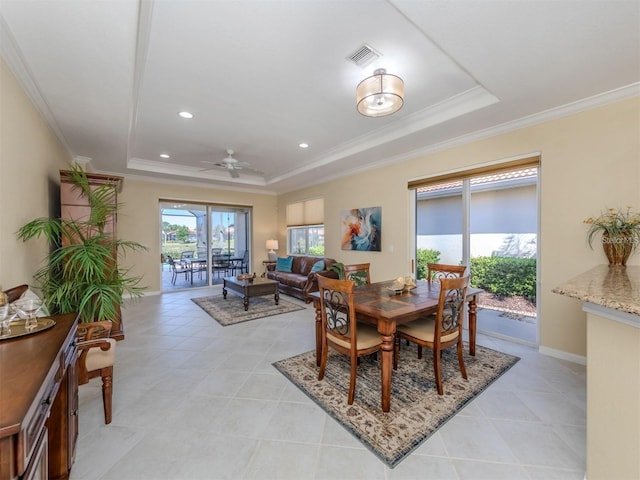 dining area with crown molding, a tray ceiling, and a healthy amount of sunlight