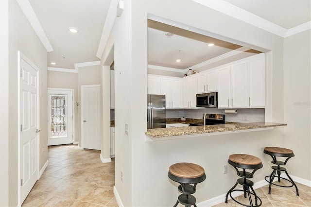 kitchen with light stone countertops, white cabinetry, appliances with stainless steel finishes, and kitchen peninsula