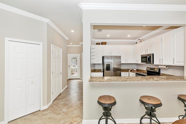 kitchen featuring appliances with stainless steel finishes, white cabinets, light stone counters, and kitchen peninsula