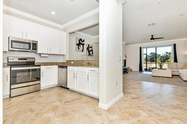 kitchen with appliances with stainless steel finishes, stone countertops, sink, white cabinets, and ornamental molding