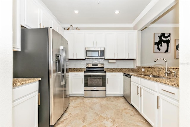 kitchen with stainless steel appliances, light stone countertops, sink, and white cabinets