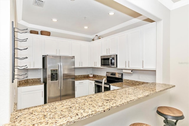 kitchen featuring white cabinetry, light stone counters, a kitchen breakfast bar, kitchen peninsula, and stainless steel appliances