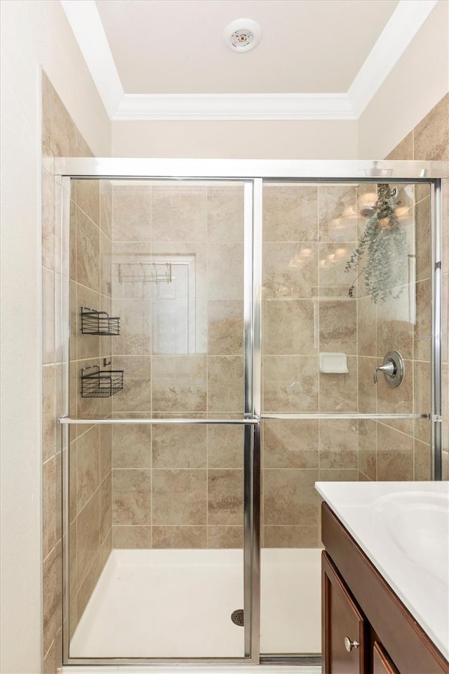 bathroom with ornamental molding, vanity, and a shower with shower door