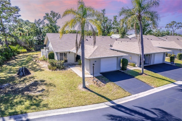 ranch-style home with a garage and a lawn