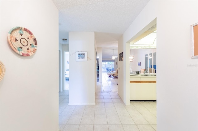 hallway with light tile patterned floors, sink, and a textured ceiling