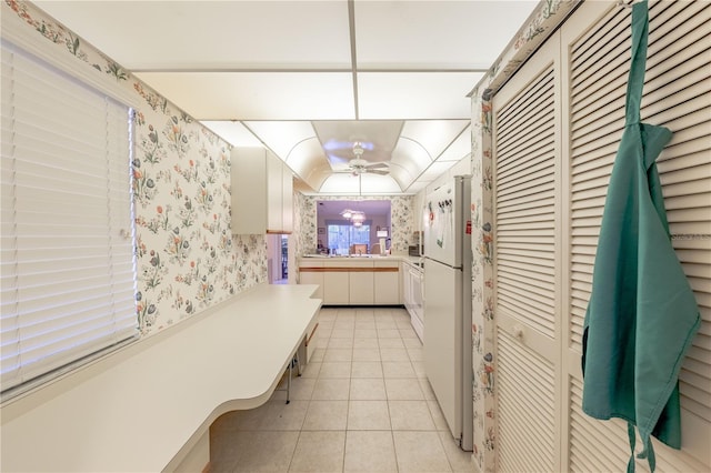 kitchen with white cabinetry, white fridge, and light tile patterned floors