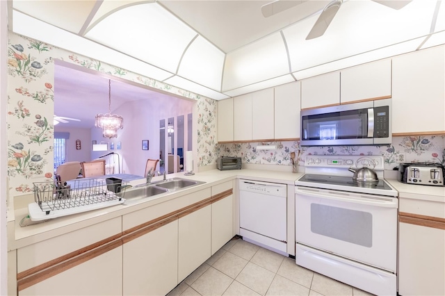 kitchen featuring sink, ceiling fan with notable chandelier, white cabinets, and white appliances