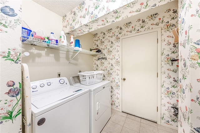 clothes washing area with separate washer and dryer, light tile patterned floors, and a textured ceiling