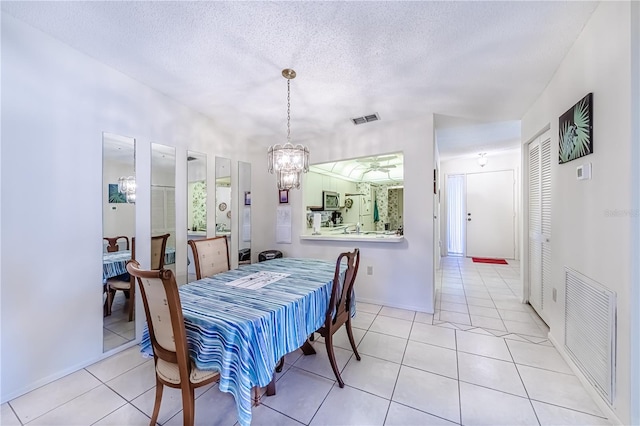 dining area featuring a notable chandelier, light tile patterned floors, and a textured ceiling