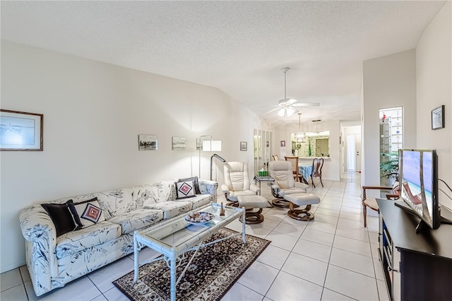 living room featuring lofted ceiling, ceiling fan, a textured ceiling, and light tile patterned flooring