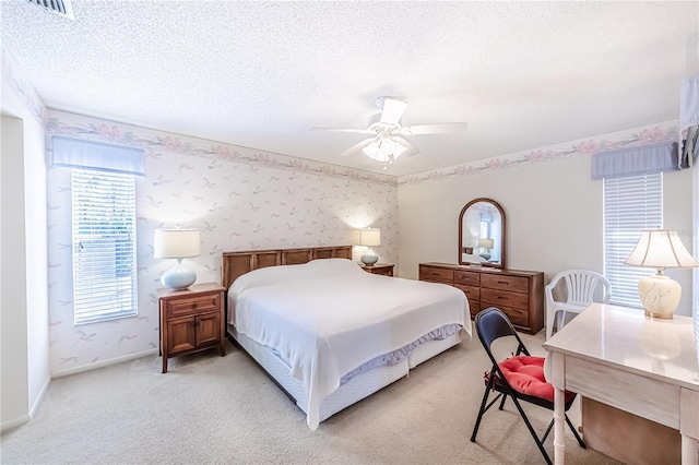 carpeted bedroom featuring ceiling fan and a textured ceiling